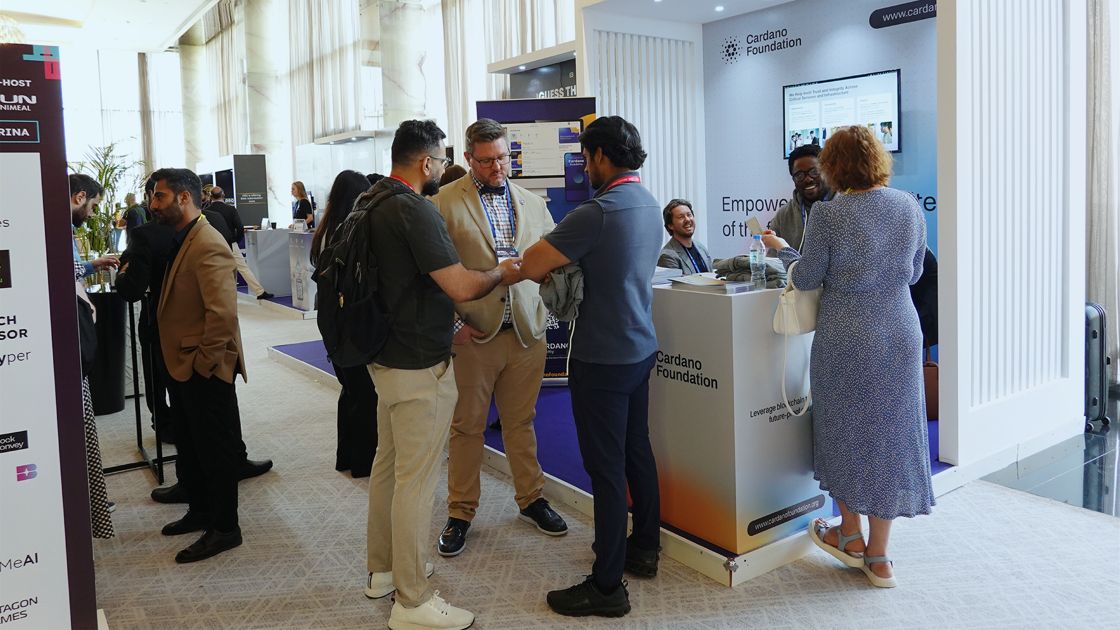 People interacting at the Cardano Foundation booth.